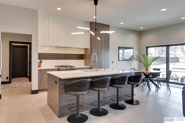 kitchen with a sink, a kitchen breakfast bar, backsplash, and modern cabinets