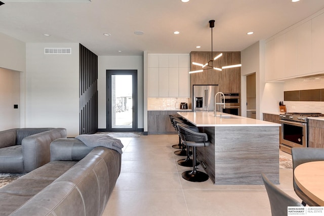 kitchen featuring modern cabinets, visible vents, backsplash, and stainless steel appliances