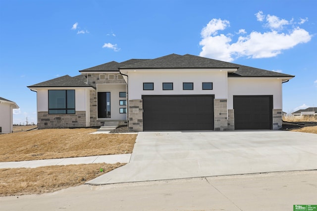 prairie-style house with concrete driveway, an attached garage, stone siding, and stucco siding