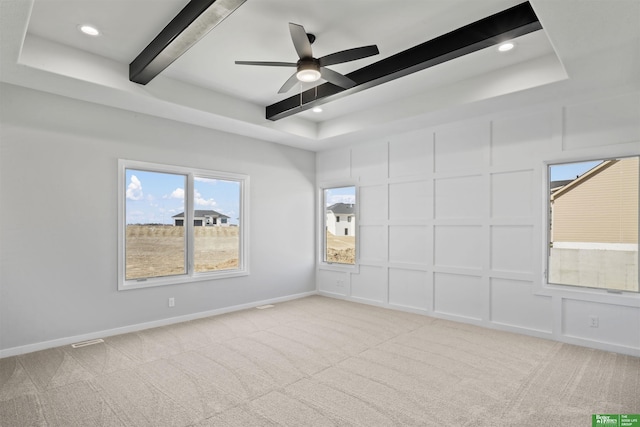 unfurnished room with a ceiling fan, carpet, beamed ceiling, baseboards, and a decorative wall