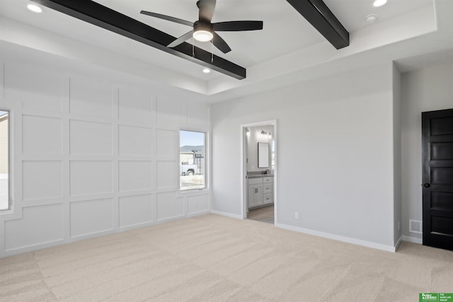 unfurnished bedroom with beamed ceiling, baseboards, light colored carpet, and a decorative wall