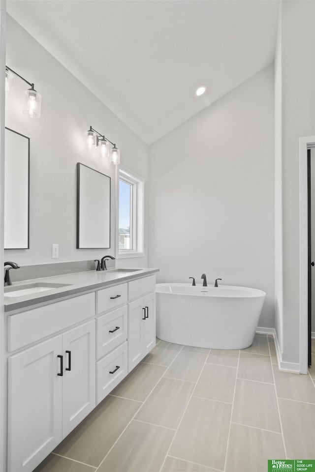 bathroom featuring a freestanding bath, double vanity, tile patterned flooring, and a sink