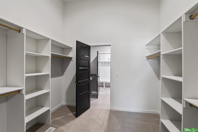 walk in closet with a towering ceiling and carpet floors