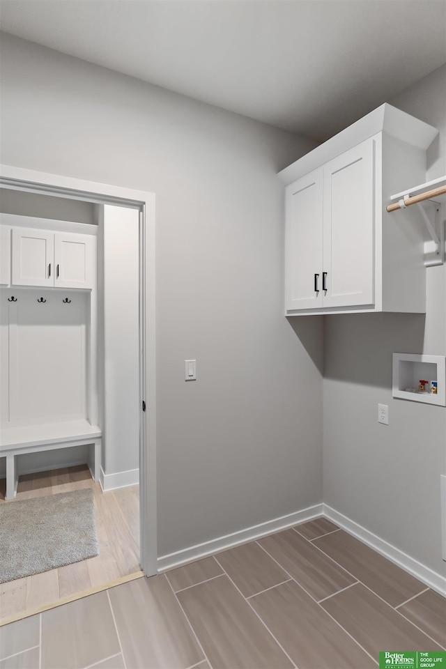 washroom featuring washer hookup, cabinet space, baseboards, and wood tiled floor