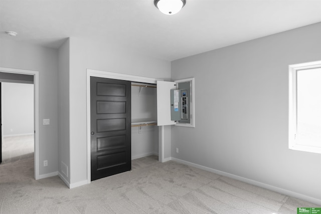 unfurnished bedroom featuring electric panel, carpet, a closet, and baseboards