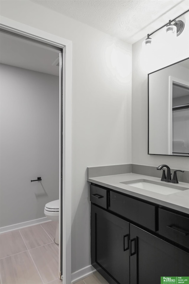 bathroom featuring vanity, baseboards, tile patterned flooring, a textured ceiling, and toilet