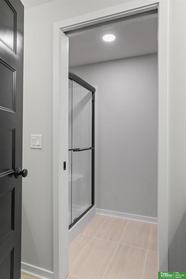 bathroom featuring baseboards, a stall shower, and tile patterned flooring