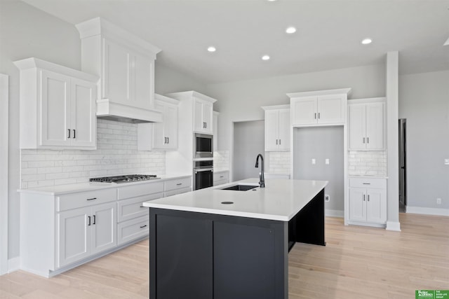 kitchen with a sink, white cabinets, light wood-style flooring, and stainless steel gas cooktop