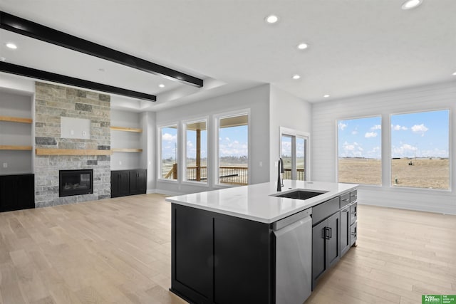 kitchen with dishwasher, dark cabinetry, light wood-style floors, and a sink