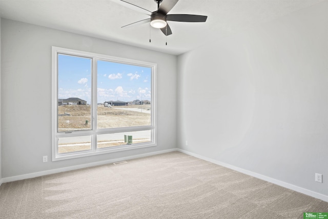 carpeted spare room with a ceiling fan and baseboards