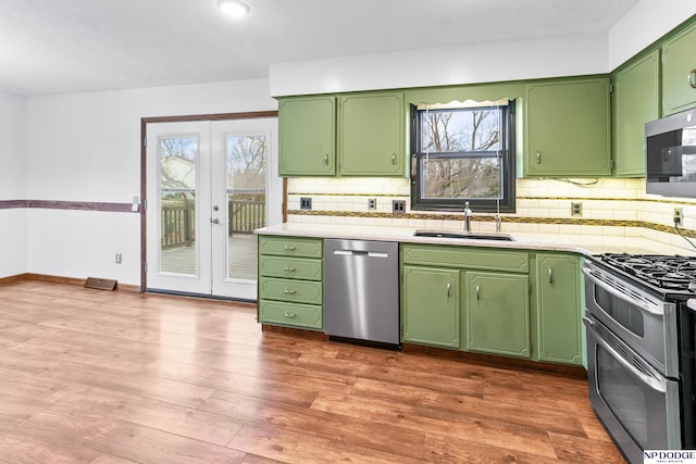 kitchen featuring green cabinets, dark wood-type flooring, light countertops, stainless steel appliances, and a sink