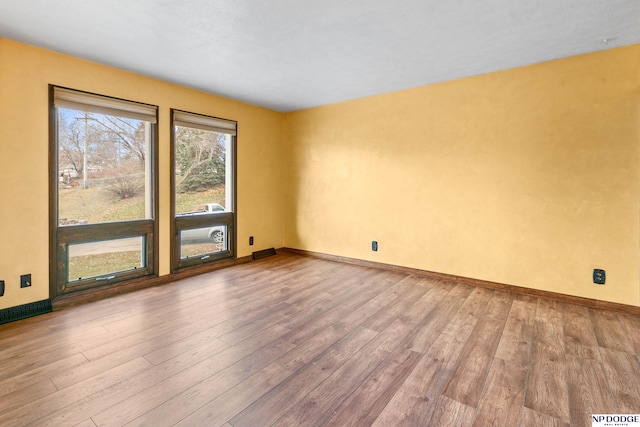 spare room featuring baseboards and wood finished floors