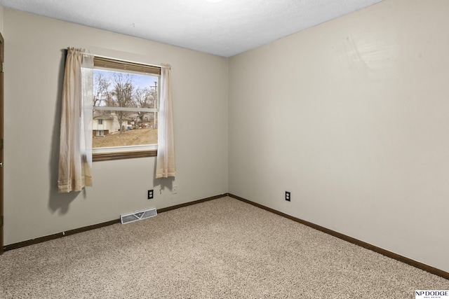 carpeted spare room with visible vents and baseboards