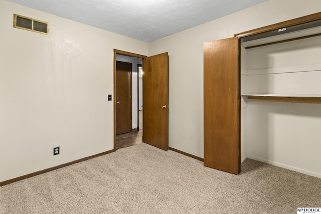 unfurnished bedroom with carpet, visible vents, baseboards, a closet, and a textured ceiling