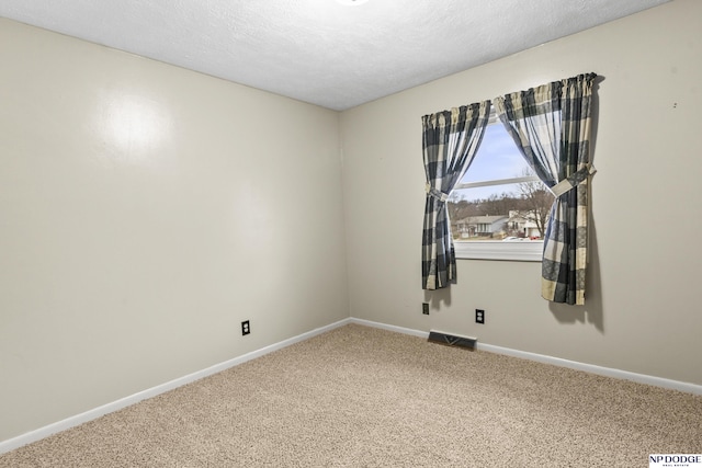 carpeted spare room with baseboards, visible vents, and a textured ceiling