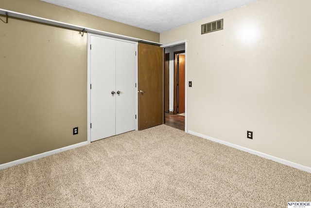 unfurnished bedroom featuring a closet, visible vents, baseboards, and carpet