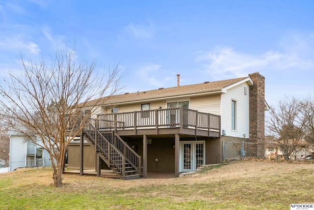 rear view of property featuring a lawn, a chimney, a deck, and fence