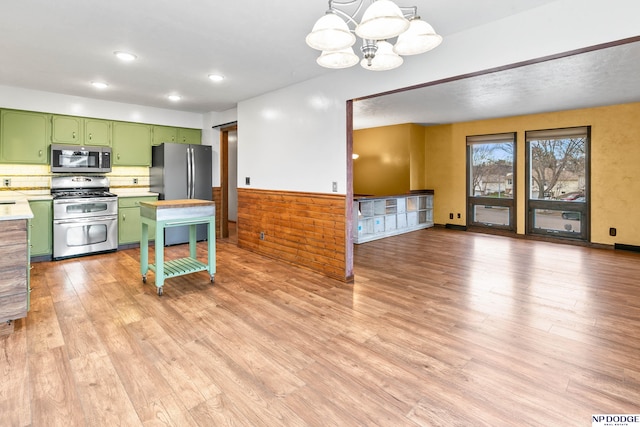 kitchen with green cabinets, light countertops, wainscoting, appliances with stainless steel finishes, and a notable chandelier