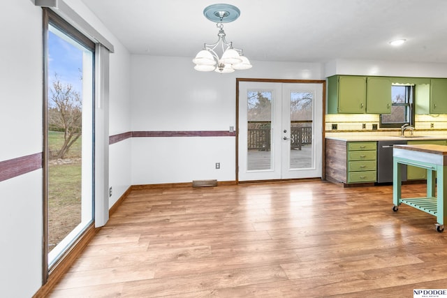 kitchen with backsplash, stainless steel dishwasher, light wood-style floors, green cabinets, and light countertops