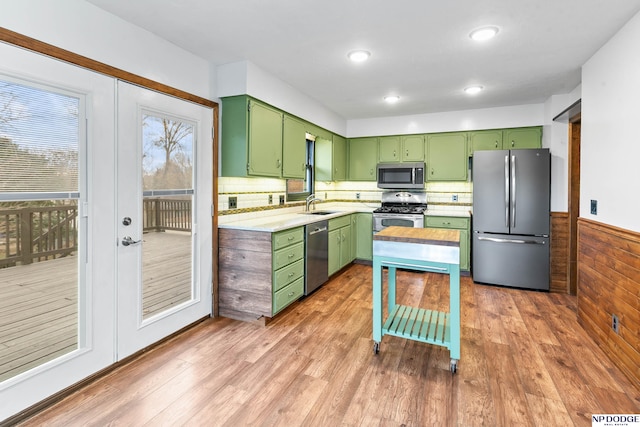 kitchen featuring wood finished floors, a sink, light countertops, appliances with stainless steel finishes, and green cabinets