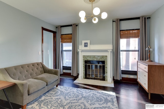 living room featuring dark wood finished floors, plenty of natural light, a stone fireplace, and an inviting chandelier