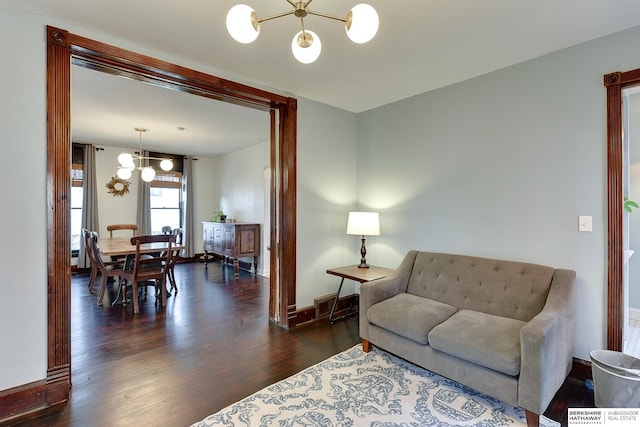 living area featuring baseboards, a notable chandelier, and wood finished floors