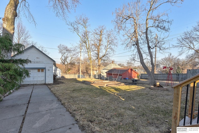 view of yard with an outdoor structure, concrete driveway, fence, and a garage