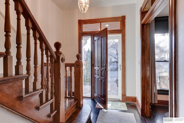 foyer entrance with stairs, baseboards, and wood finished floors