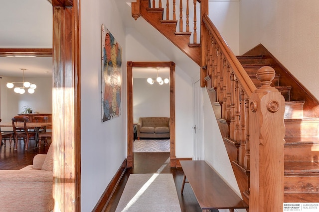 staircase with a chandelier, baseboards, and wood finished floors