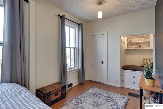 bedroom featuring baseboards, a textured ceiling, and wood finished floors