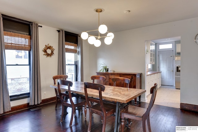 dining space with a notable chandelier, visible vents, baseboards, and wood finished floors