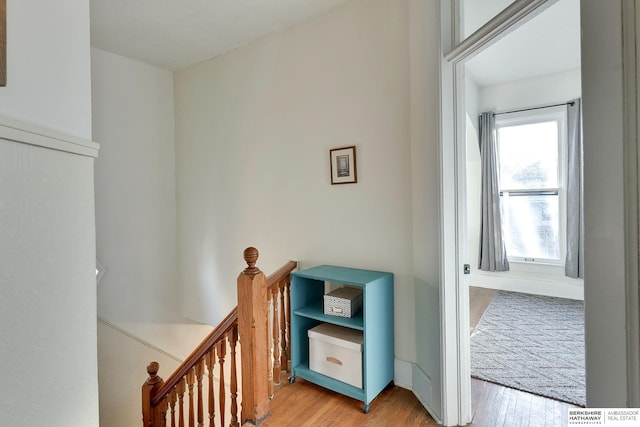 hallway with an upstairs landing and wood finished floors