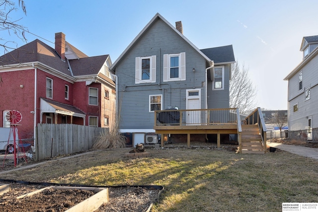 rear view of house with a yard, a deck, a chimney, and fence