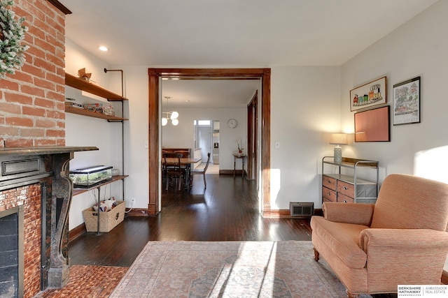 living room featuring visible vents, baseboards, a brick fireplace, and hardwood / wood-style floors