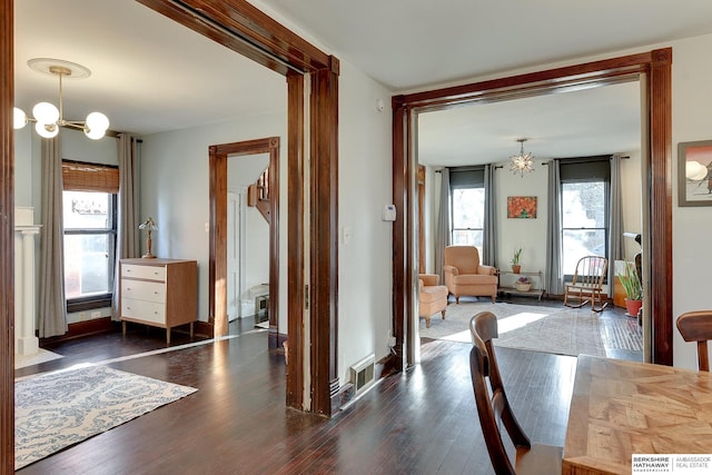 dining room with a notable chandelier, baseboards, visible vents, and wood finished floors