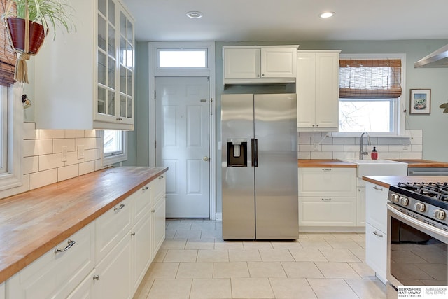 kitchen with tasteful backsplash, butcher block countertops, stainless steel appliances, and a sink