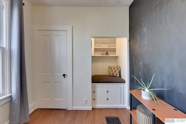 office with visible vents, baseboards, a textured ceiling, and light wood finished floors