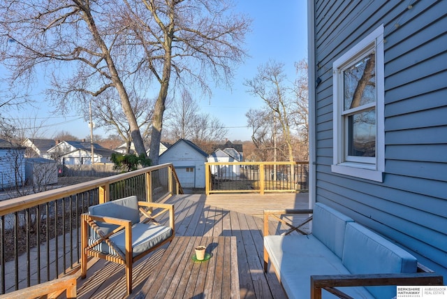 wooden deck featuring an outdoor structure, a garage, fence, and a residential view