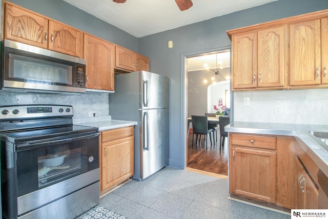 kitchen featuring baseboards, granite finish floor, stainless steel appliances, light countertops, and tasteful backsplash