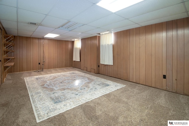 finished basement featuring a drop ceiling, carpet floors, wooden walls, and visible vents