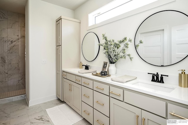 full bath with a sink, marble finish floor, double vanity, and a tile shower