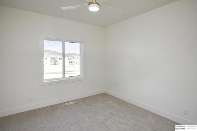 empty room featuring visible vents, carpet floors, baseboards, and a ceiling fan