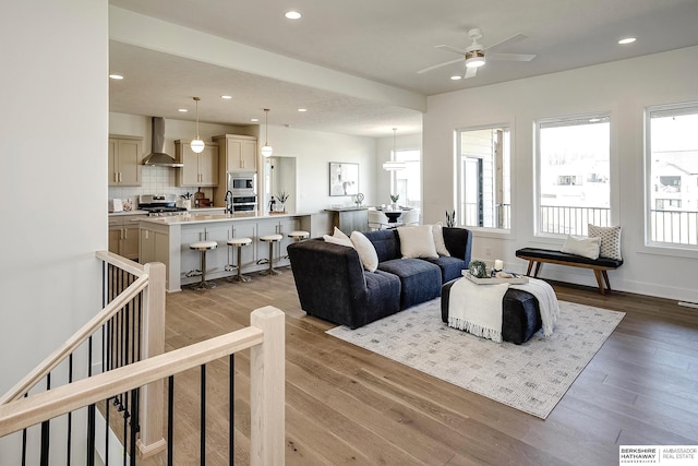 living area featuring a ceiling fan, light wood-style flooring, recessed lighting, and baseboards