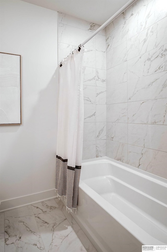 bathroom featuring baseboards, marble finish floor, and shower / bath combo