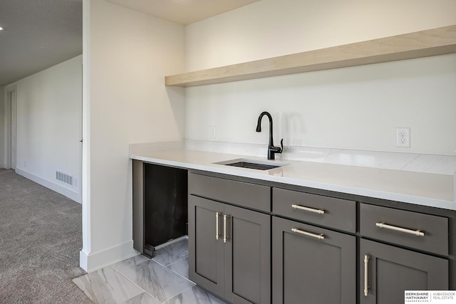 kitchen with visible vents, marble finish floor, gray cabinets, a sink, and light countertops
