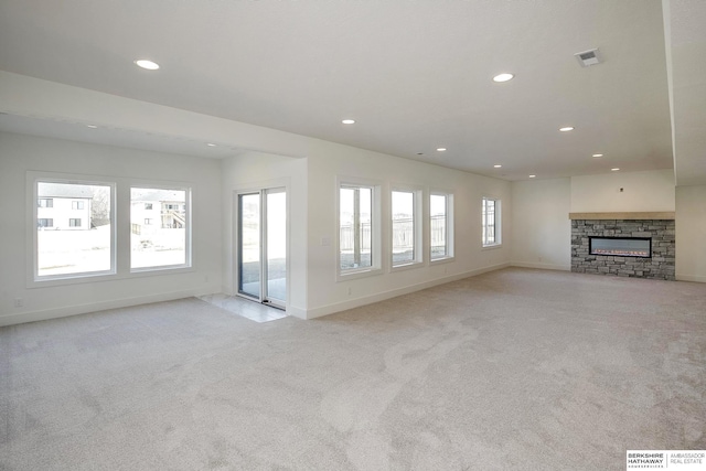 unfurnished living room featuring visible vents, light colored carpet, and a healthy amount of sunlight