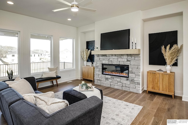living area with a stone fireplace, recessed lighting, a ceiling fan, and wood finished floors