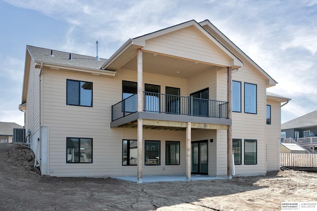 back of property with central AC unit, a shingled roof, and a patio