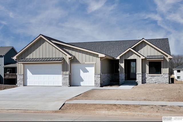 view of front of house featuring driveway, a shingled roof, a garage, stone siding, and board and batten siding