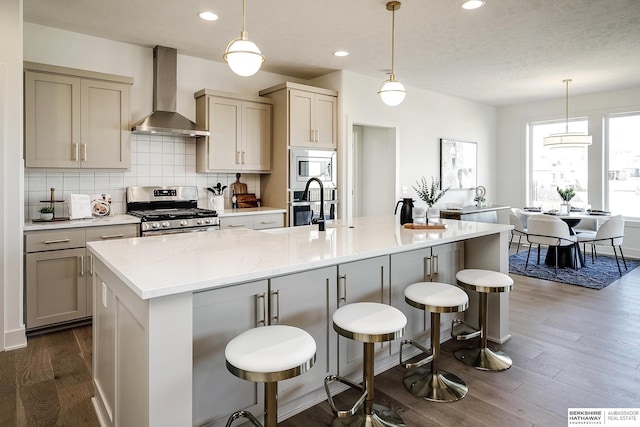 kitchen with decorative backsplash, dark wood-type flooring, wall chimney range hood, and appliances with stainless steel finishes